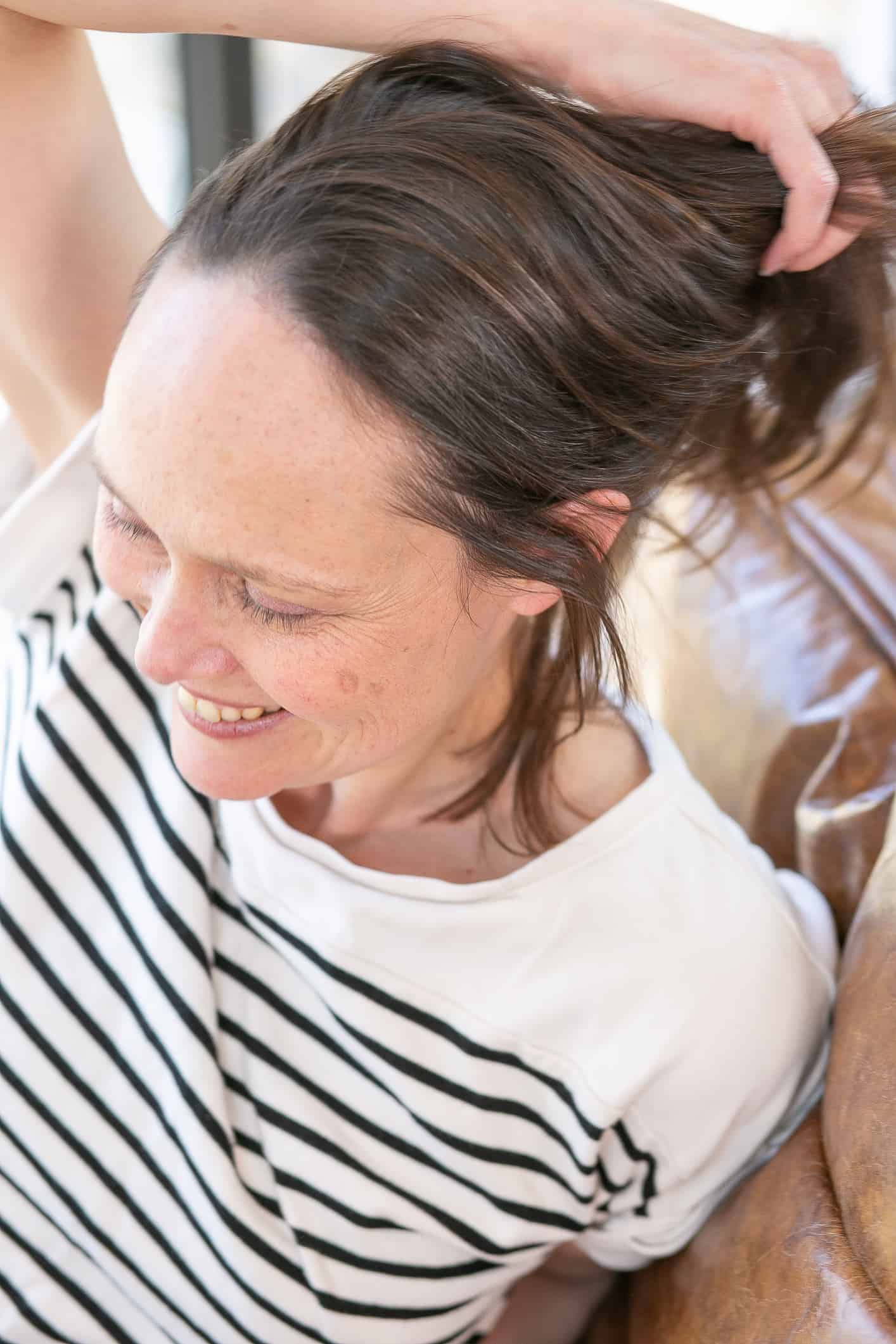 steph mcgee hypnotherapist wearing a white top with black horizontal stripes and relaxing in the therapy chair