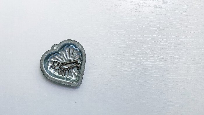 sliver heart locket containing two small keys, sitting on a plain white background that represents stilling the conscious mind at the heart of all hypnobirthing techniques