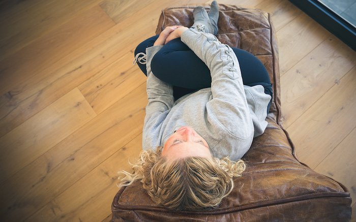 hypnotherapy-for-fertility-session white middle age blonde woman relaxing on a brown leather recliner in black leggings and grey sweatshirt during a hypnotherapy for her first fertility session
