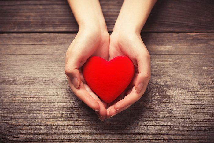 hypnotherapy oxytocin a white womans hands holding a red heart shape to demostrate the love hormones needs to for conception and fertility