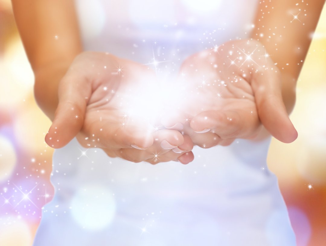 the magic of ivf hypnosis in the hands of a slim white woman wearing a white vest top and holding a beautiful shining light in her hands
